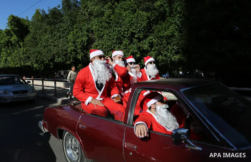 Palestinians dressed as Santa Claus ride a red car to welcome the new year, in the streets of Gaza City, New Year's Eve revellers on December 31, 2017. Photo by Ashraf Amra