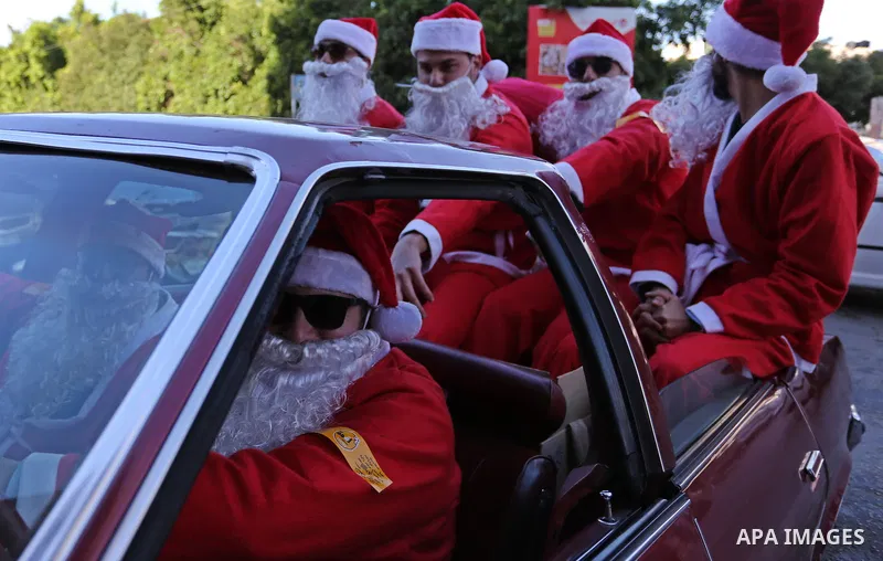 Palestinians dressed as Santa Claus ride a red car to welcome the new year, in the streets of Gaza City, New Year's Eve revellers on December 31, 2017. Photo by Ashraf Amra