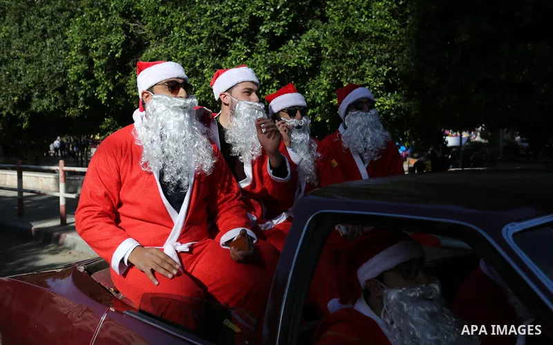 Palestinians dressed as Santa Claus ride a red car to welcome the new year, in the streets of Gaza City, New Year's Eve revellers on December 31, 2017. Photo by Ashraf Amra