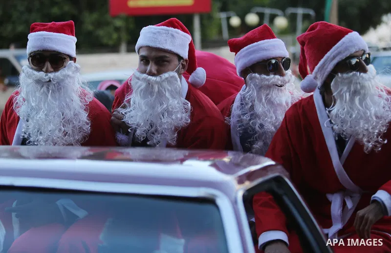 Palestinians dressed as Santa Claus ride a red car to welcome the new year, in the streets of Gaza City, New Year's Eve revellers on December 31, 2017. Photo by Ashraf Amra