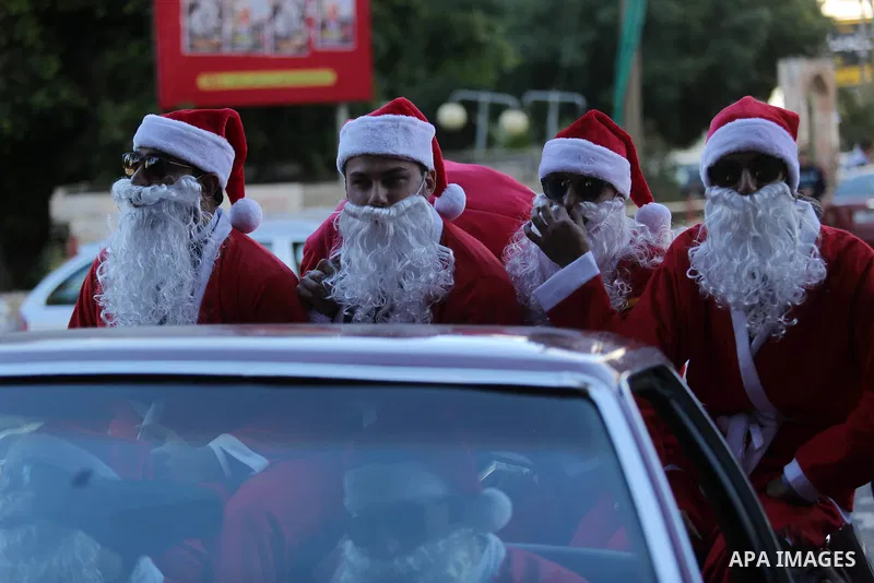 Palestinians dressed as Santa Claus ride a red car to welcome the new year, in the streets of Gaza City, New Year's Eve revellers on December 31, 2017. Photo by Ashraf Amra
