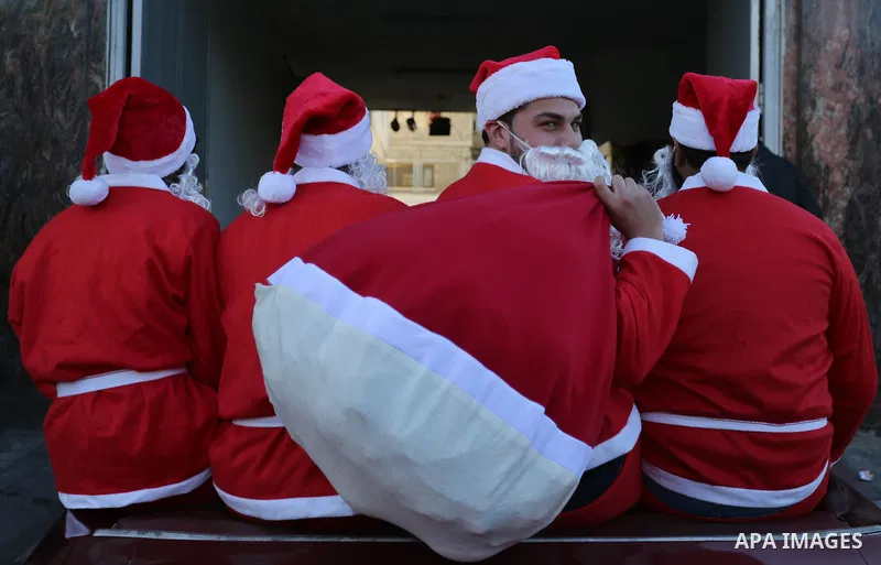 Palestinians dressed as Santa Claus ride a red car to welcome the new year, in the streets of Gaza City, New Year's Eve revellers on December 31, 2017. Photo by Ashraf Amra