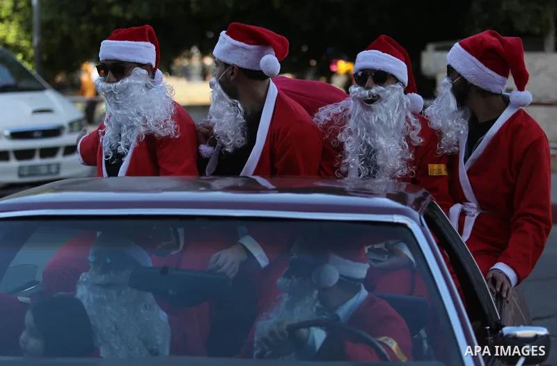 Palestinians dressed as Santa Claus ride a red car to welcome the new year, in the streets of Gaza City, New Year's Eve revellers on December 31, 2017. Photo by Ashraf Amra