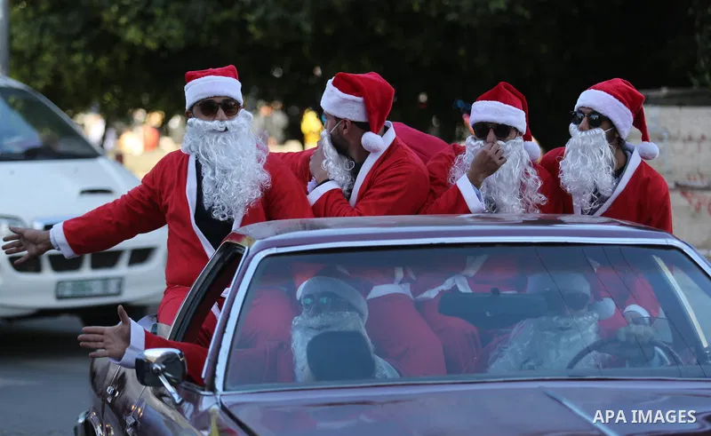 Palestinians dressed as Santa Claus ride a red car to welcome the new year, in the streets of Gaza City, New Year's Eve revellers on December 31, 2017. Photo by Ashraf Amra