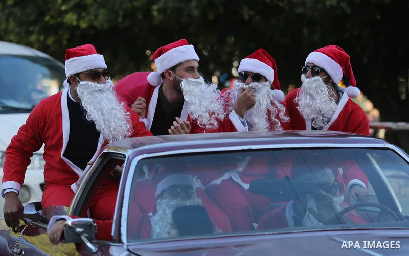 Palestinians dressed as Santa Claus ride a red car to welcome the new year, in the streets of Gaza City, New Year's Eve revellers on December 31, 2017. Photo by Ashraf Amra