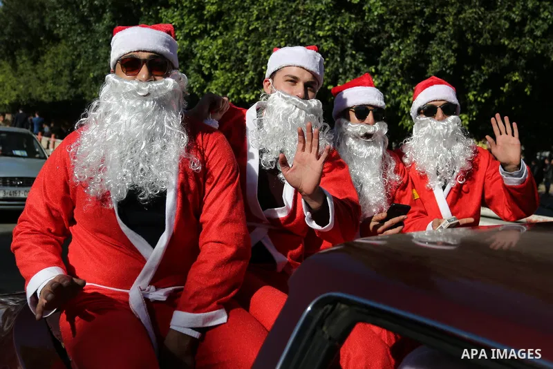 Palestinians dressed as Santa Claus ride a red car to welcome the new year, in the streets of Gaza City, New Year's Eve revellers on December 31, 2017. Photo by Ashraf Amra