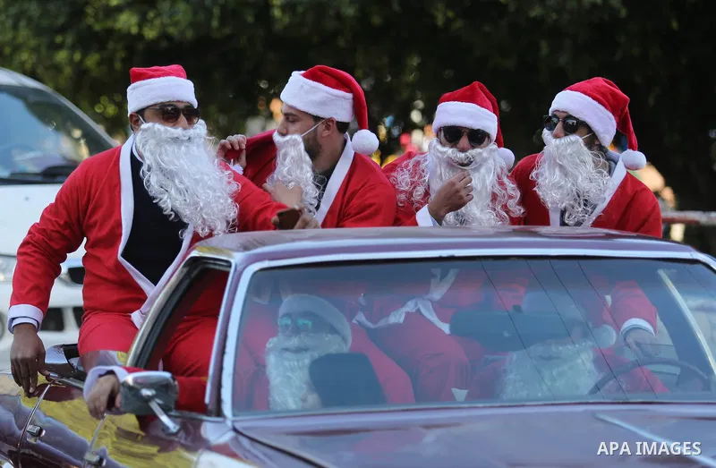 Palestinians dressed as Santa Claus ride a red car to welcome the new year, in the streets of Gaza City, New Year's Eve revellers on December 31, 2017. Photo by Ashraf Amra