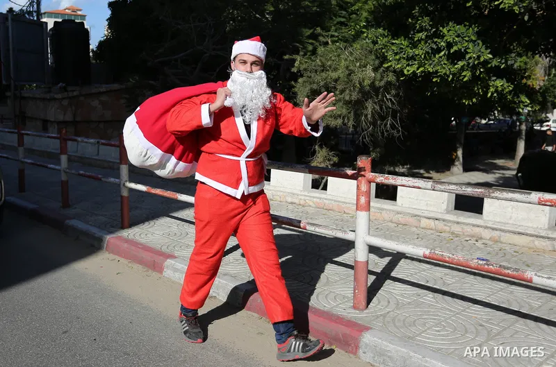 A Palestinian dressed as Santa Claus celebarats to welcome the new year, in the streets of Gaza City, New Year's Eve revellers on December 31, 2017. Photo by Ashraf Amra