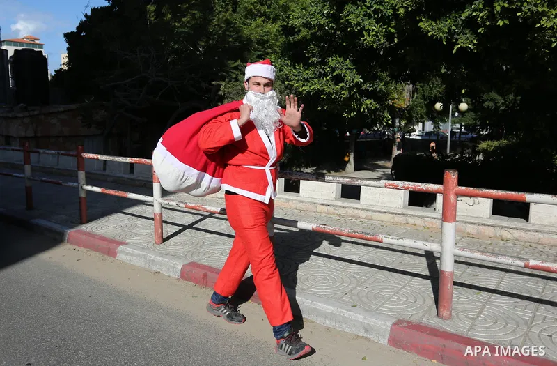 A Palestinian dressed as Santa Claus celebrates to welcome the new year, in the streets of Gaza City, New Year's Eve revellers on December 31, 2017. Photo by Ashraf Amra