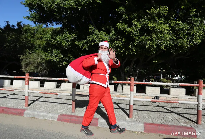 A Palestinian dressed as Santa Claus celebrates to welcome the new year, in the streets of Gaza City, New Year's Eve revellers on December 31, 2017. Photo by Ashraf Amra