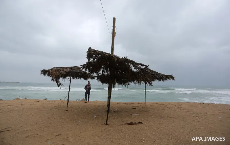 A Palestinian man walks during a rainy day at seaport of Gaza city on January 1, 2018. Photo by Ashraf Amra
