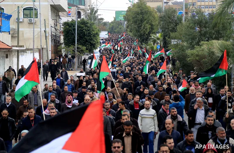 Palestinian employees of Gaza strip hold banners and Palestine flags during a demonstration demanding their rights, in Gaza city, on January 2, 2018. Photo by Atia Darwish