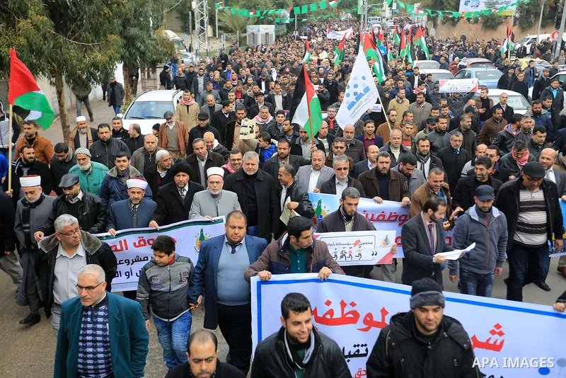Palestinian employees of Gaza strip hold banners and Palestine flags during a demonstration demanding their rights, in Gaza city, on January 2, 2018. Photo by Atia Darwish