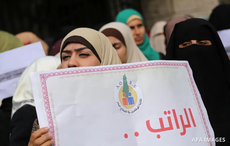 Palestinian employees of Gaza strip hold banners and Palestine flags during a demonstration demanding their rights, in Gaza city, on January 2, 2018. Photo by Mohammed Asad
