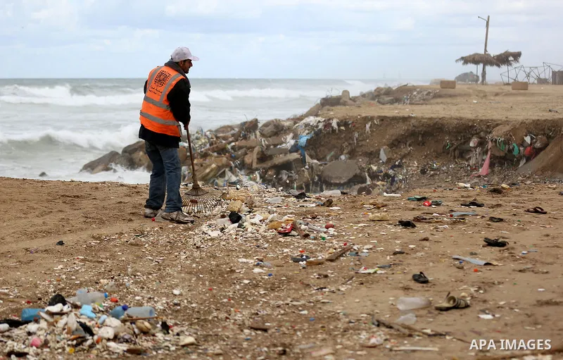 A Palestinian man collects gravel and stones at the beach in Gaza city after storm hit the region to sell to customers on January 6, 2018. Photo by Yasser Qudih