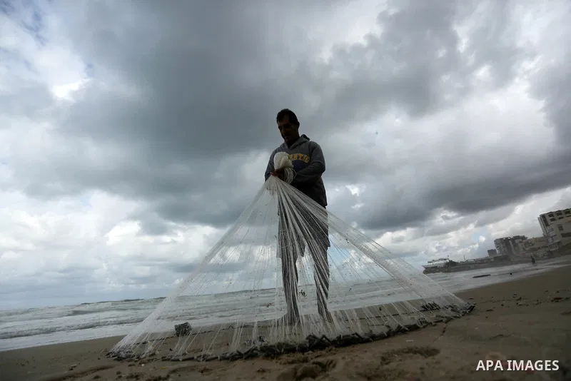 A Palestinian fisherman prepares his fishing nets on a beach in Gaza City on January 6, 2018. Photo by Ashraf Amra