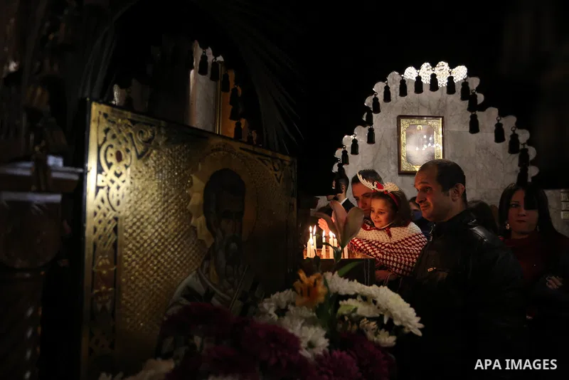 Palestinias light a candle during an Orthodox Christmas mass at the Saint Porfirios church in Gaza City January 7, 2018. Photo by Ashraf Amra