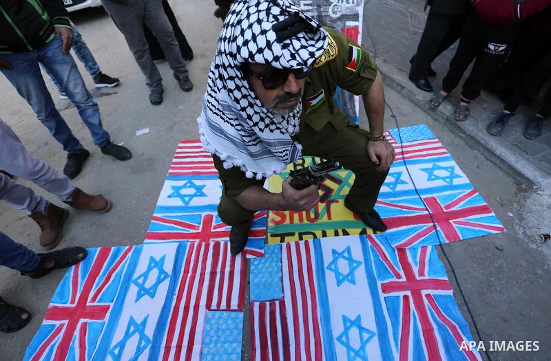 Palestinians burn an Israeli flag and a U.S. flag during a protest to show solidarity with Palestinian prisoners held in Israeli jails, in front of Red cross office in Gaza city, on January 8, 2018. Photo by Ashraf Amra