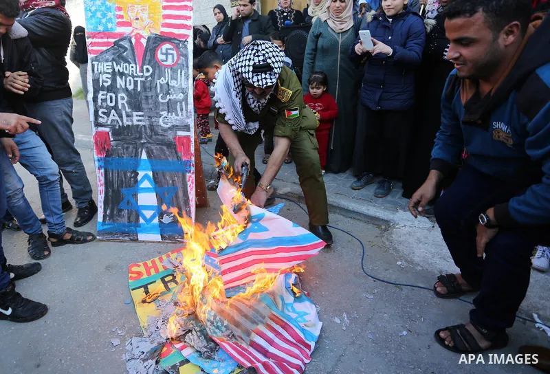 Palestinians burn an Israeli flag and a U.S. flag during a protest to show solidarity with Palestinian prisoners held in Israeli jails, in front of Red cross office in Gaza city, on January 8, 2018. Photo by Ashraf Amra