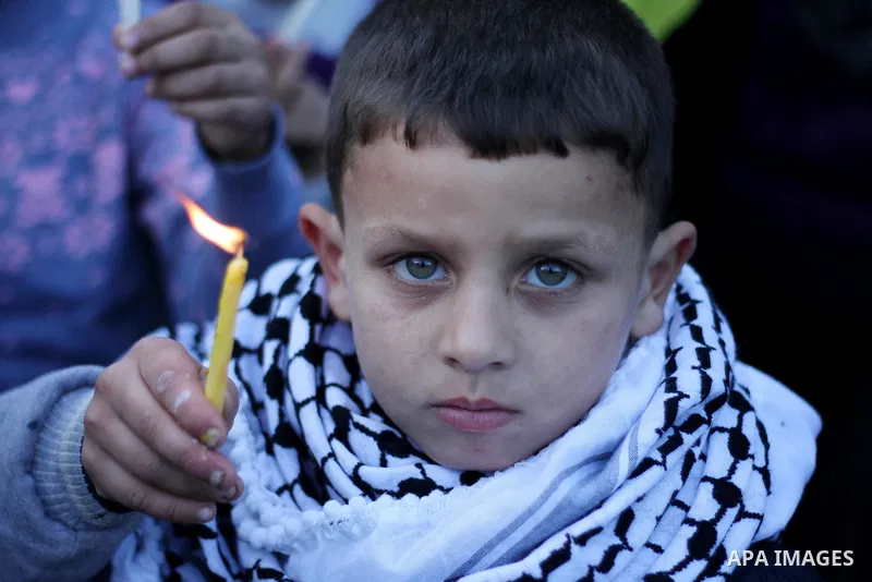 A Palestinian boy holds a candle during a protest in support of Palestinian teenager Ahed Tamimi, 16-year-old in Gaza city on January 8, 2018. Israel charged Tamimi with 12 counts including assault on January 1 following...