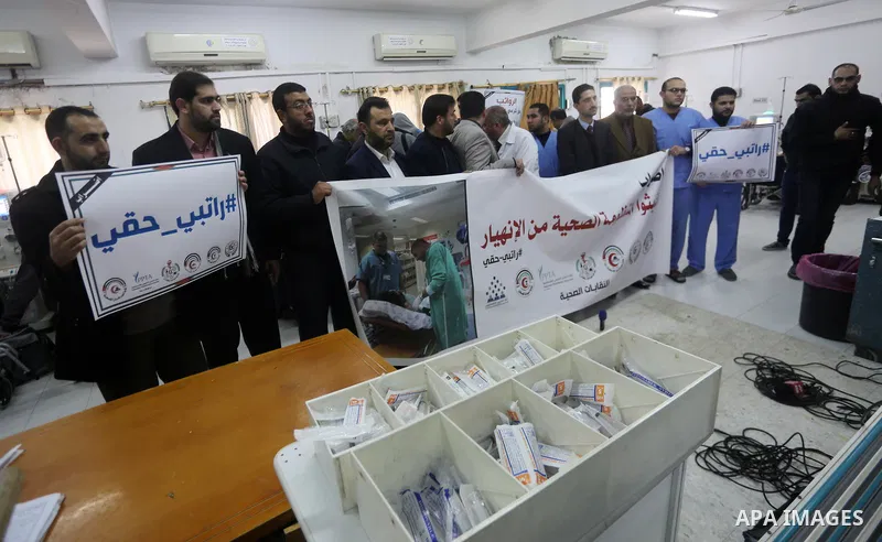 Palestinian doctors hold banners during a protest to demand their salaries, at the Al-Shifa hospital in Gaza City on January 9, 2018. Photo by Mohammed Asad