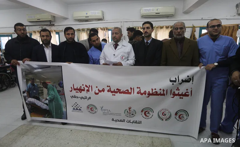 Palestinian doctors hold banners during a protest to demand their salaries, at the Al-Shifa hospital in Gaza City on January 9, 2018. Photo by Mohammed Asad