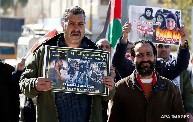Palestinian protesters hold placards during a demonstration to show solidarity with Palestinian prisoners held in Israeli jails near Israel's controversial separation barrier in the West Bank city of Bethlehem, on Janura...