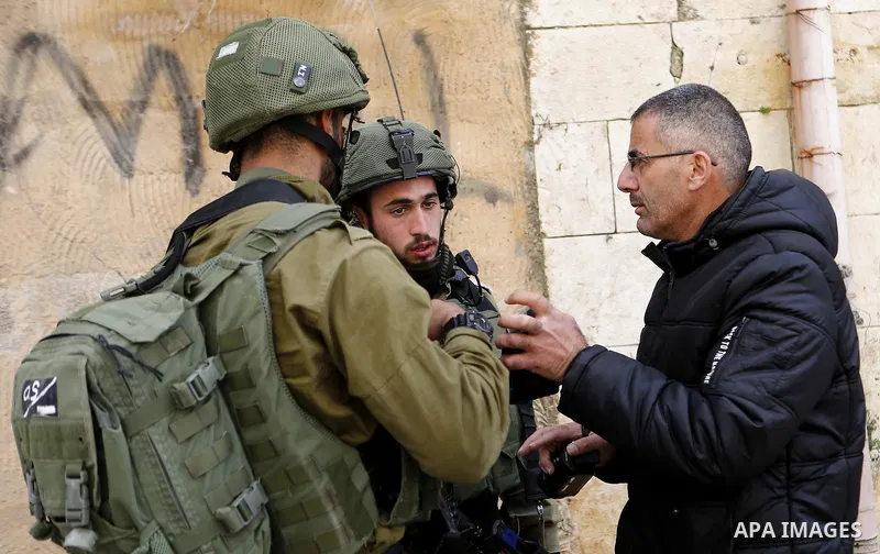 Israeli security forces check the identity of Palestinians in the Old town in the West Bank city of Hebron on January 14, 2018. Photo by Wisam Hashlamoun