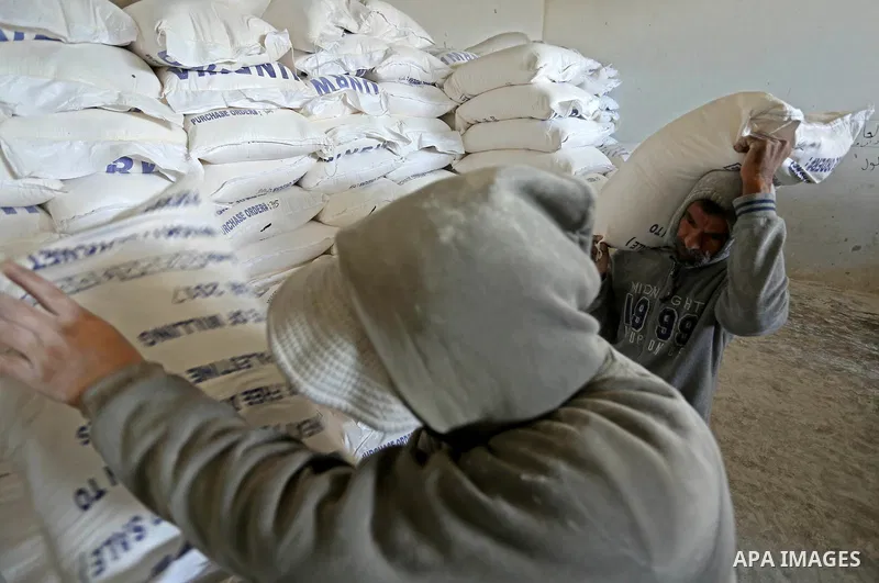 Palestinian men carry sacks of flour at a United Nations food distribution center in Khan Younis in the southern Gaza Strip January 15, 2018. U.S. President Donald Trump is preparing to withhold tens of millions of dolla...