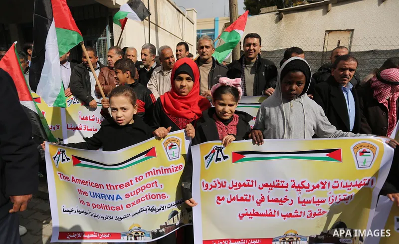 Palestinians hold banners during a protest against aid cut, in front of the headquarters United Nations Relief and Works Agency (UNRWA) in al-Nusirat refugee camp in the Gaza strip on January 17, 2018 after the White Hou...