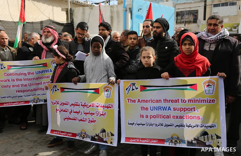 Palestinians hold banners during a protest against aid cut, in front of the headquarters United Nations Relief and Works Agency (UNRWA) in al-Nusirat refugee camp in the Gaza strip on January 17, 2018 after the White Hou...