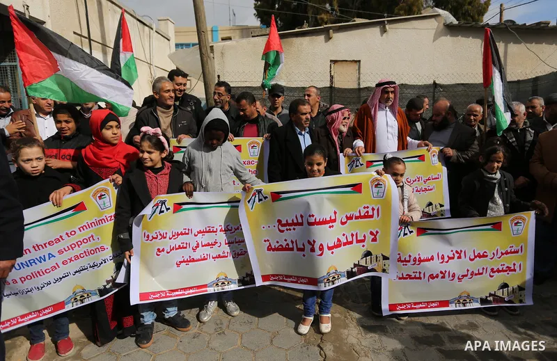 Palestinians hold banners during a protest against aid cut, in front of the headquarters United Nations Relief and Works Agency (UNRWA) in al-Nusirat refugee camp in the Gaza strip on January 17, 2018 after the White Hou...