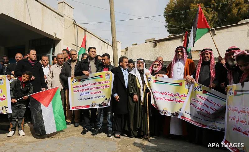 Palestinians hold banners during a protest against aid cut, in front of the headquarters United Nations Relief and Works Agency (UNRWA) in al-Nusirat refugee camp in the Gaza strip on January 17, 2018 after the White Hou...