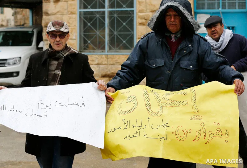 Palestinians hold banners during a protest, outside the headquarters United Nations Relief and Works Agency (UNRWA) in the West Bank city of Hebron on January 17, 2018, after the White House froze tens of millions of dol...