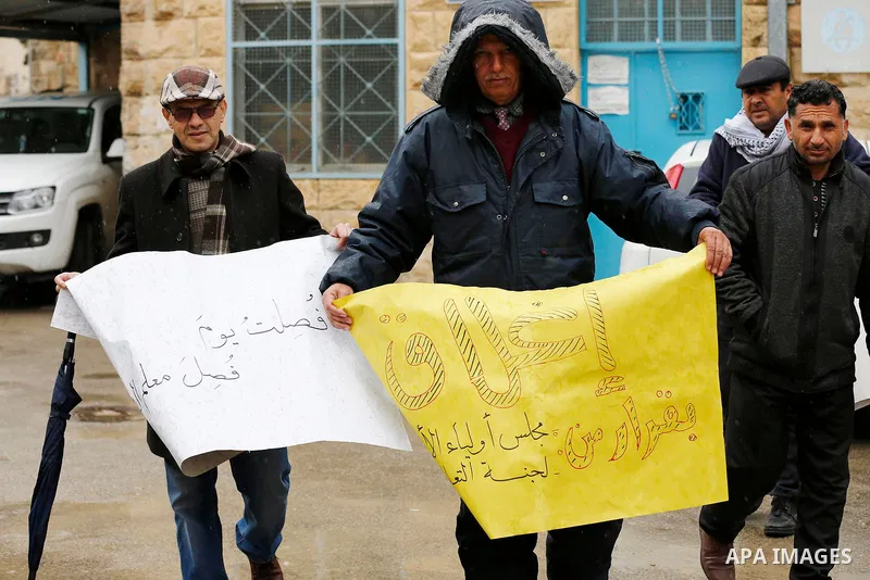 Palestinians hold banners during a protest, outside the headquarters United Nations Relief and Works Agency (UNRWA) in the West Bank city of Hebron on January 17, 2018, after the White House froze tens of millions of dol...