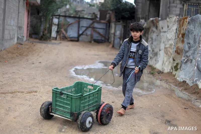 A Palestinian boy plays outside his family house during a rainy day in Beit Lahiya in the north of the Gaza strip on January 17, 2018. Photo by Ramez Habboub