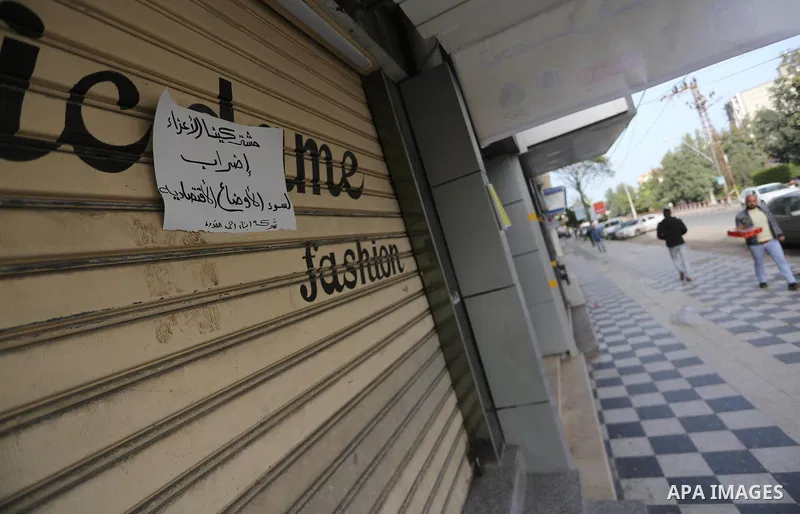 Palestinians walk past closed shops during a general strike in Gaza city on January 22, 2018. Gazans are strapped for cash and markets are suffering from an unprecedented recession. Meanwhile, on Dec. 30, for the first t...