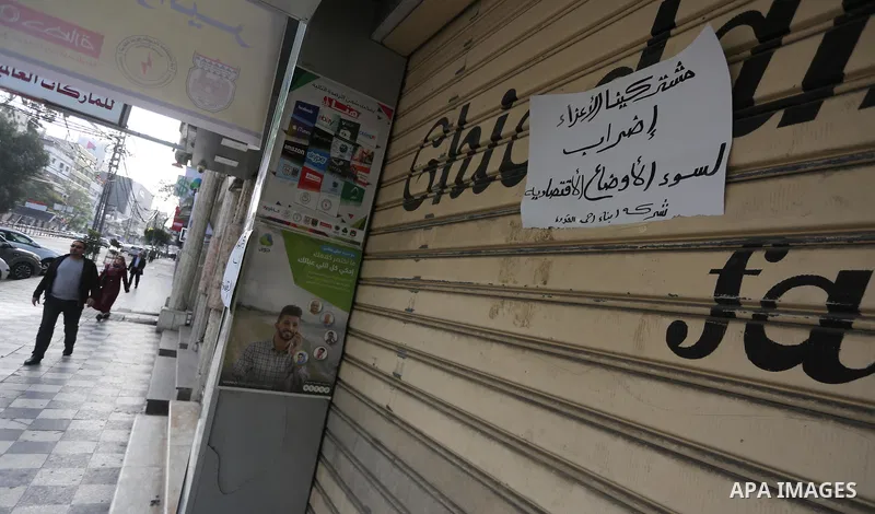 Palestinians walk past closed shops during a general strike in Gaza city on January 22, 2018. Gazans are strapped for cash and markets are suffering from an unprecedented recession. Meanwhile, on Dec. 30, for the first t...