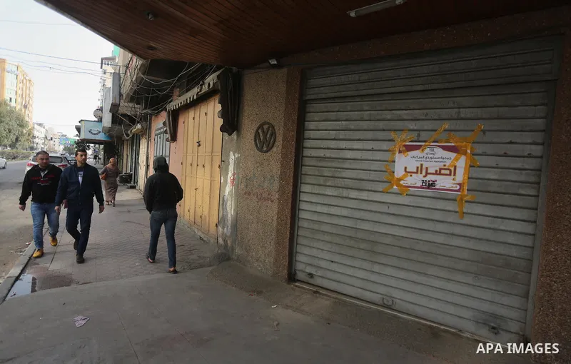 Palestinians walk past closed shops during a general strike in Gaza city on January 22, 2018. Gazans are strapped for cash and markets are suffering from an unprecedented recession. Meanwhile, on Dec. 30, for the first t...