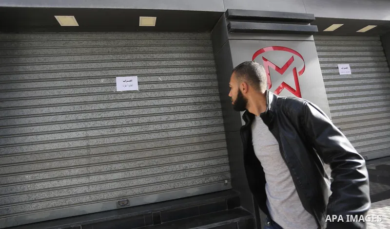 A Palestinian walks past closed shops during a general strike in Gaza city on January 22, 2018. Gazans are strapped for cash and markets are suffering from an unprecedented recession. Meanwhile, on Dec. 30, for the first...