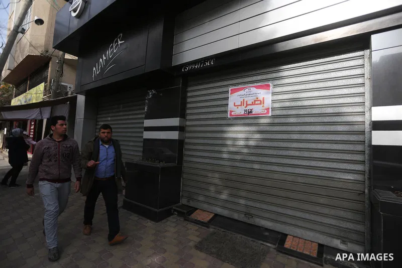 Palestinians walk past closed shops during a general strike in Gaza city on January 22, 2018. Gazans are strapped for cash and markets are suffering from an unprecedented recession. Meanwhile, on Dec. 30, for the first t...