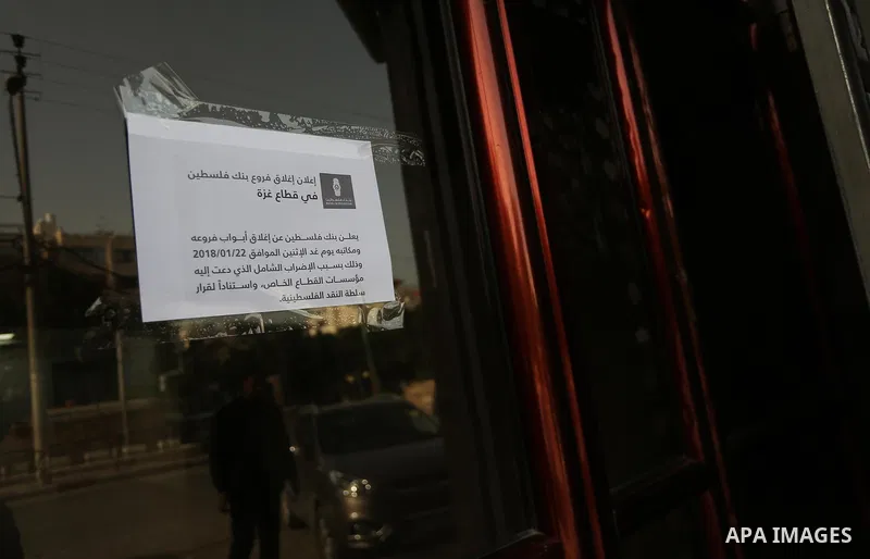 A Palestinian walks past closed shops during a general strike in Gaza city on January 22, 2018. Gazans are strapped for cash and markets are suffering from an unprecedented recession. Meanwhile, on Dec. 30, for the first...