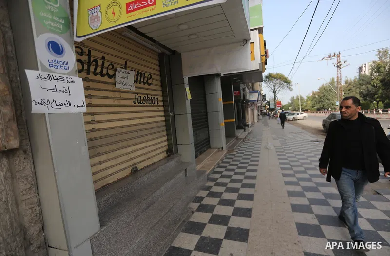 A Palestinian walks past closed shops during a general strike in Gaza city on January 22, 2018. Gazans are strapped for cash and markets are suffering from an unprecedented recession. Meanwhile, on Dec. 30, for the first...
