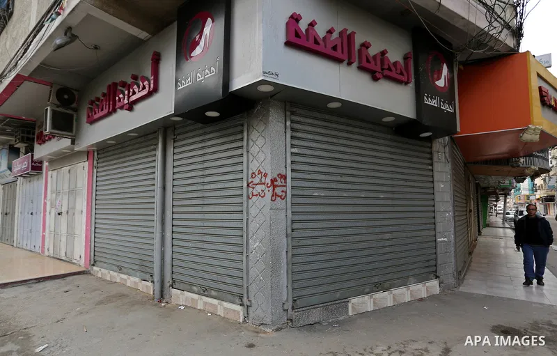 A Palestinian walks past closed shops during a commercial strike in protest against the economic situation, in Gaza city on January 23, 2018. Photo by Ashraf Amra