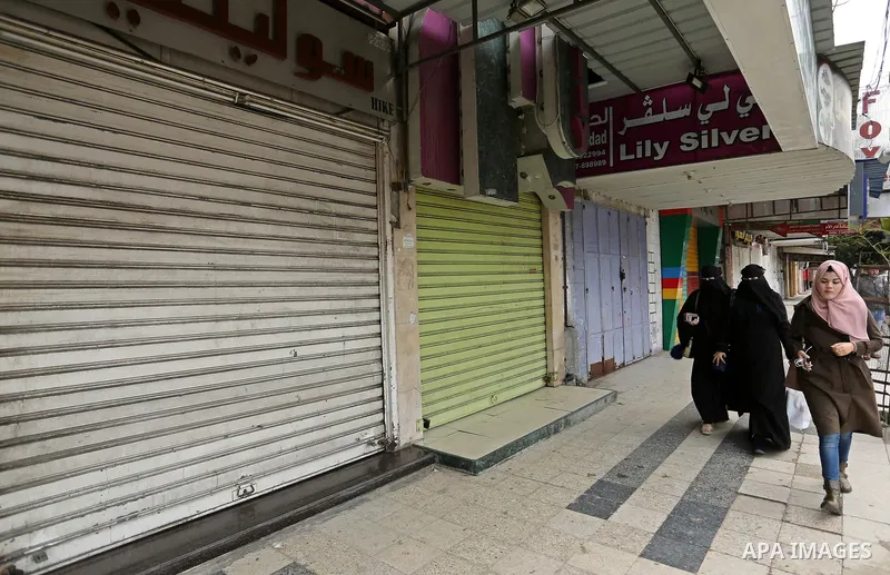 Palestinians walk past closed shops during a commercial strike in protest against the economic situation, in Gaza city on January 23, 2018. Photo by Ashraf Amra