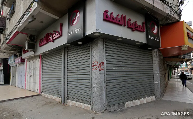 A Palestinian walks past closed shops during a commercial strike in protest against the economic situation, in Gaza city on January 23, 2018. Photo by Ashraf Amra