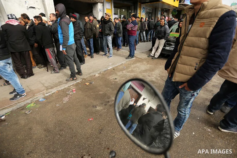 Palestinians of Social Affairs wait in front of Bank of Palestine to withdrew their financial aid in Gaza City on January 23, 2018. Photo by Ashraf Amra