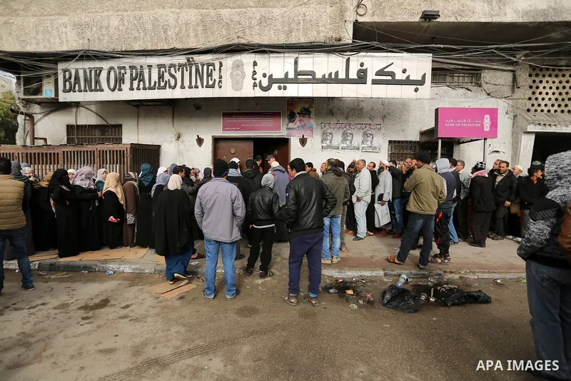 Palestinians of Social Affairs wait in front of Bank of Palestine to withdrew their financial aid in Gaza City on January 23, 2018. Photo by Ashraf Amra