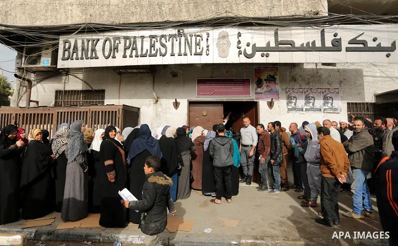 Palestinians of Social Affairs wait in front of Bank of Palestine to withdrew their financial aid in Gaza City on January 23, 2018. Photo by Ashraf Amra