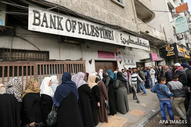 Palestinians of Social Affairs wait in front of Bank of Palestine to withdrew their financial aid in Gaza City on January 23, 2018. Photo by Ashraf Amra